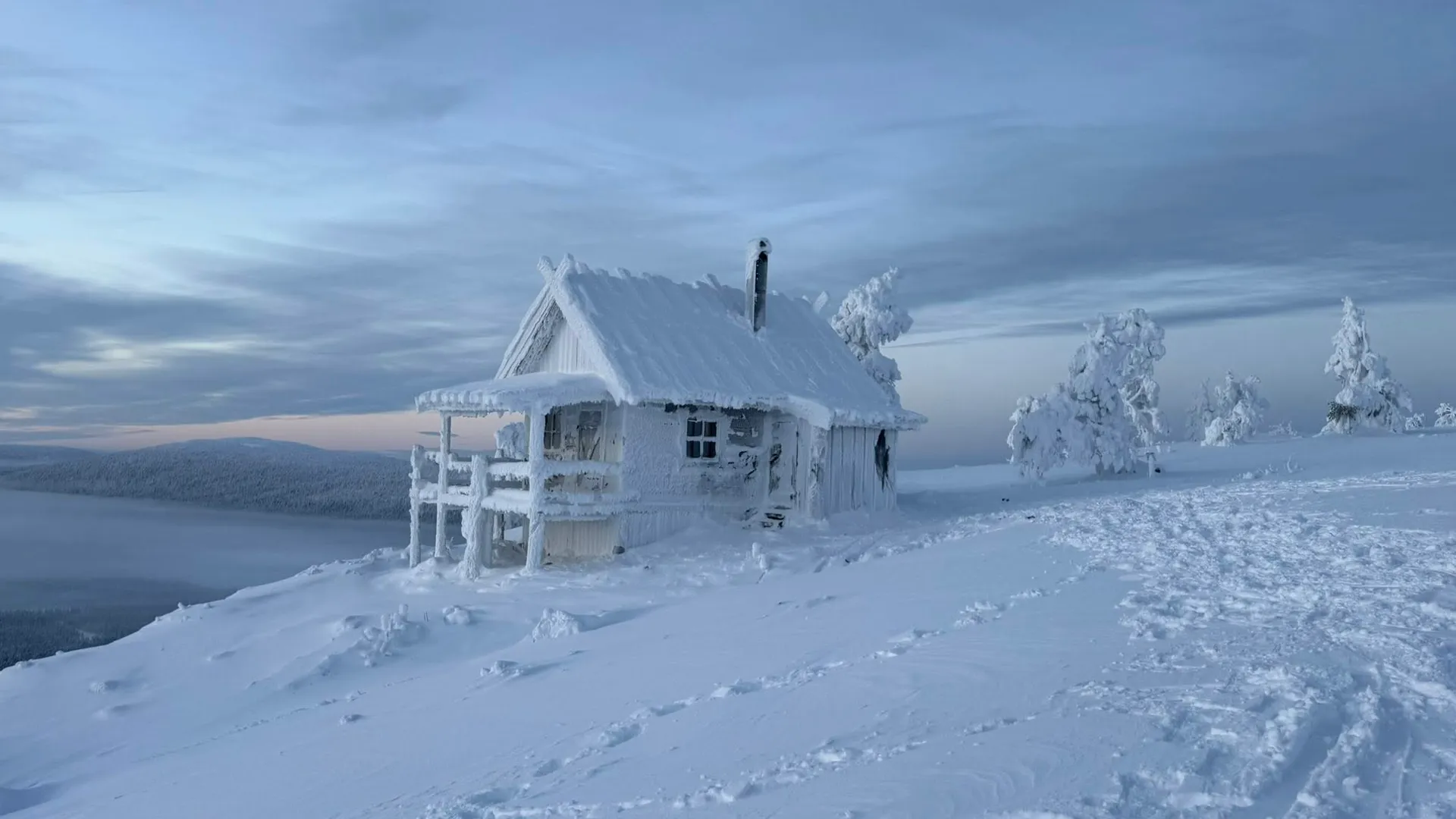 Snow-covered wooden hut on a fell top in Finnish Lapland at winter dusk