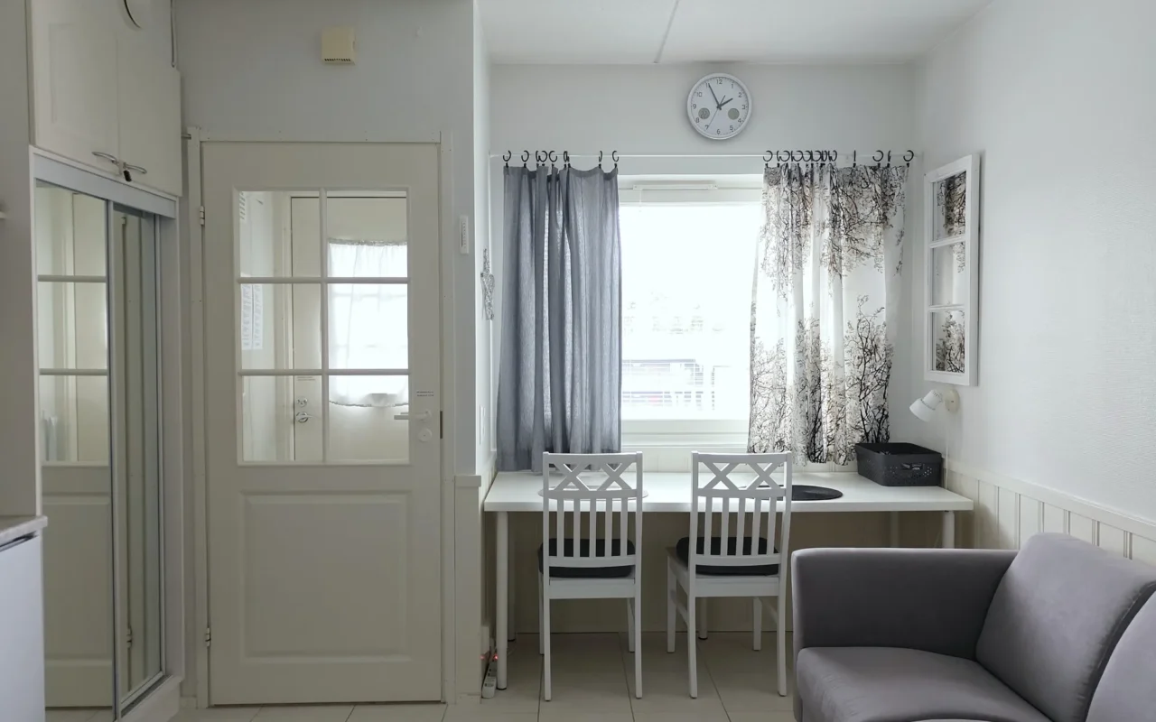 Window desk with two chairs, sofa and entrance door in the 21 m² B apartment in Levi