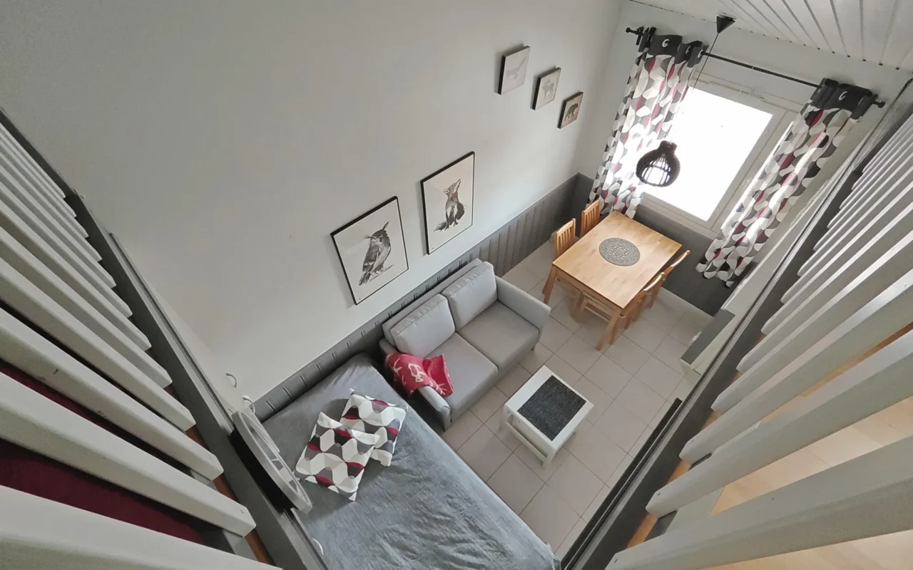 Dining table by the window and kitchenette seen from the loft in the 27 m² A apartment