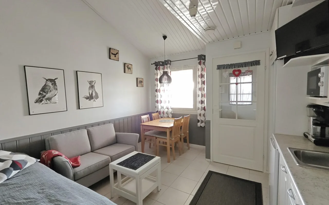 Dining table, grey sofa and bed with animal prints on the wall in the 27 m² A apartment, Levi