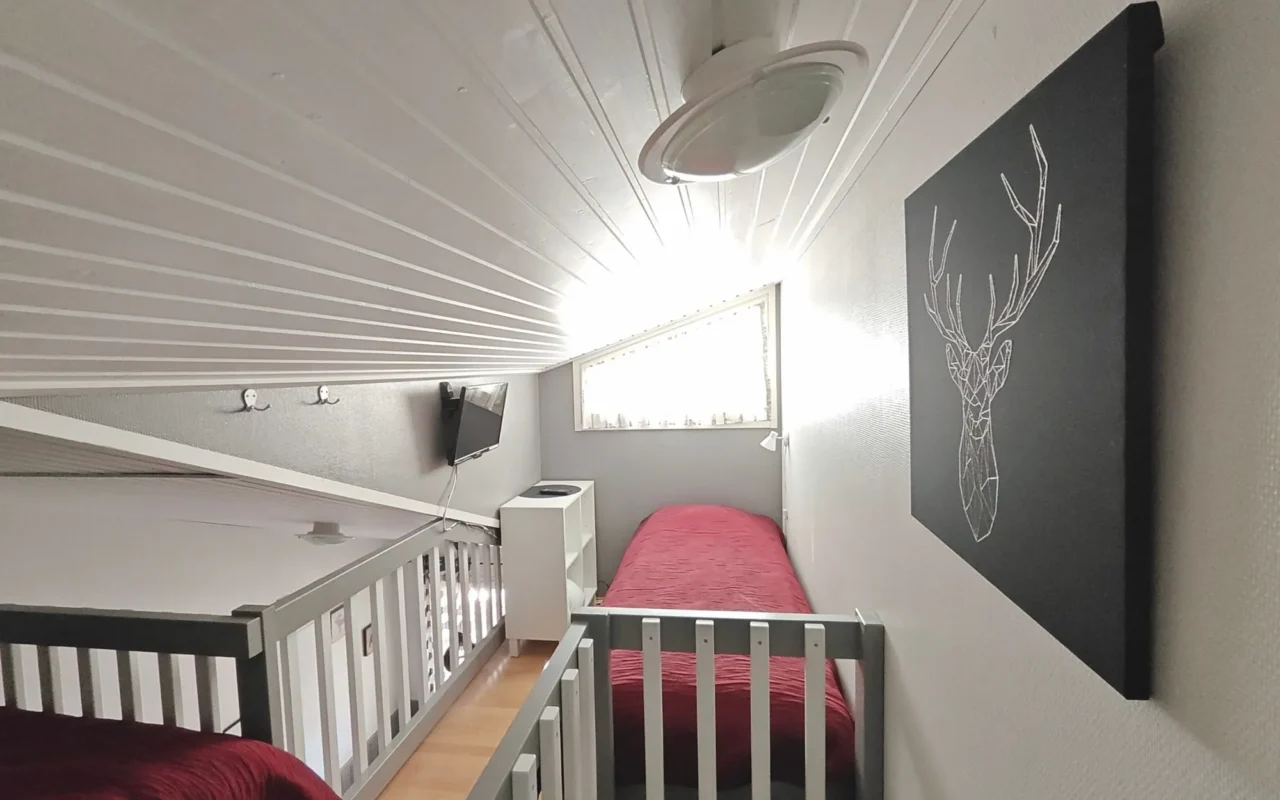 Single bed in the loft under a window with a stag print on the wall, 27 m² A, Levi