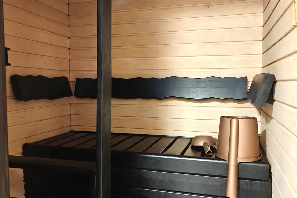 Private sauna with dark benches and wooden panelling in the 27 m² A apartment, Levi